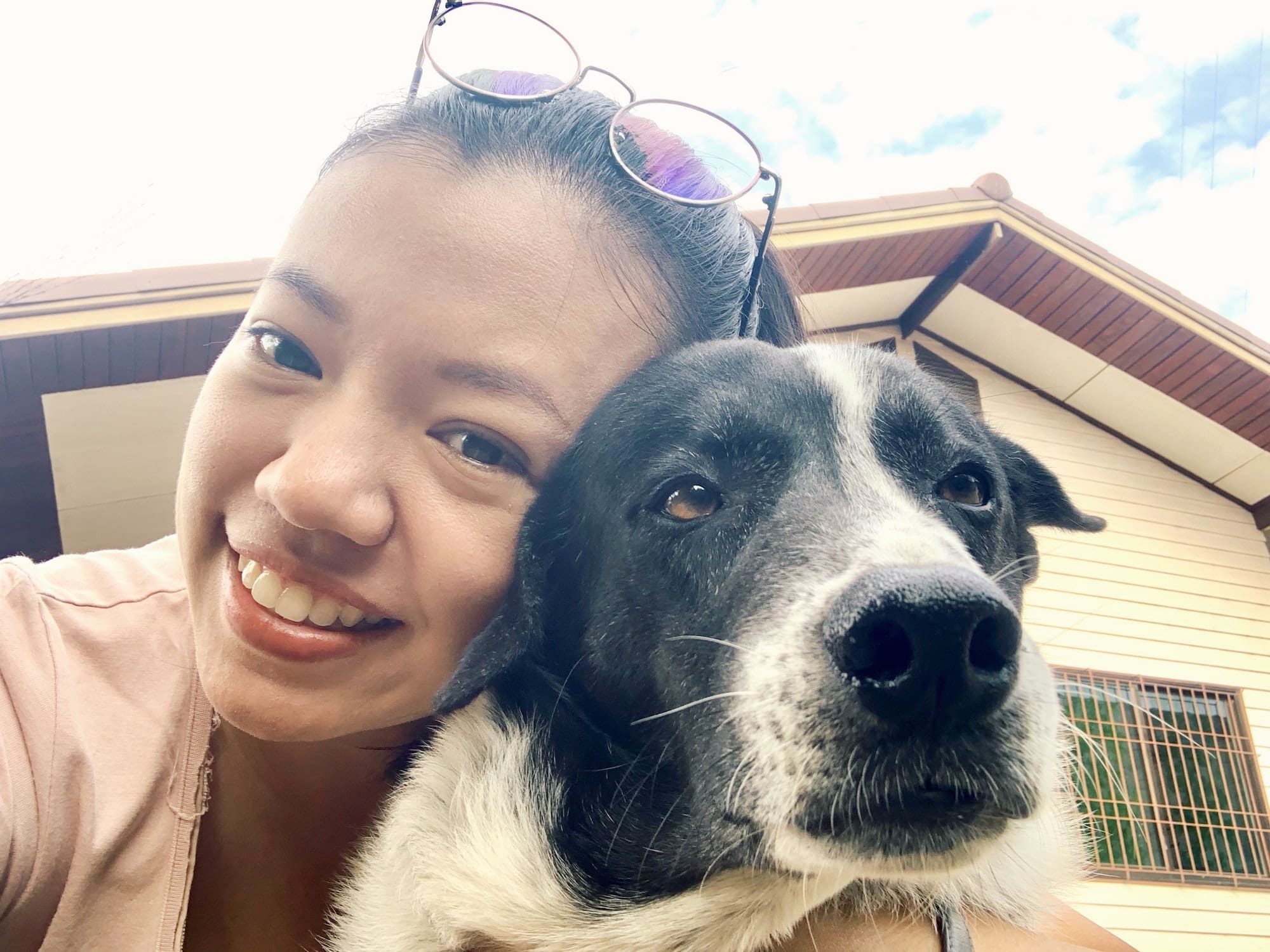 Selfie of dog and owner in front of house.